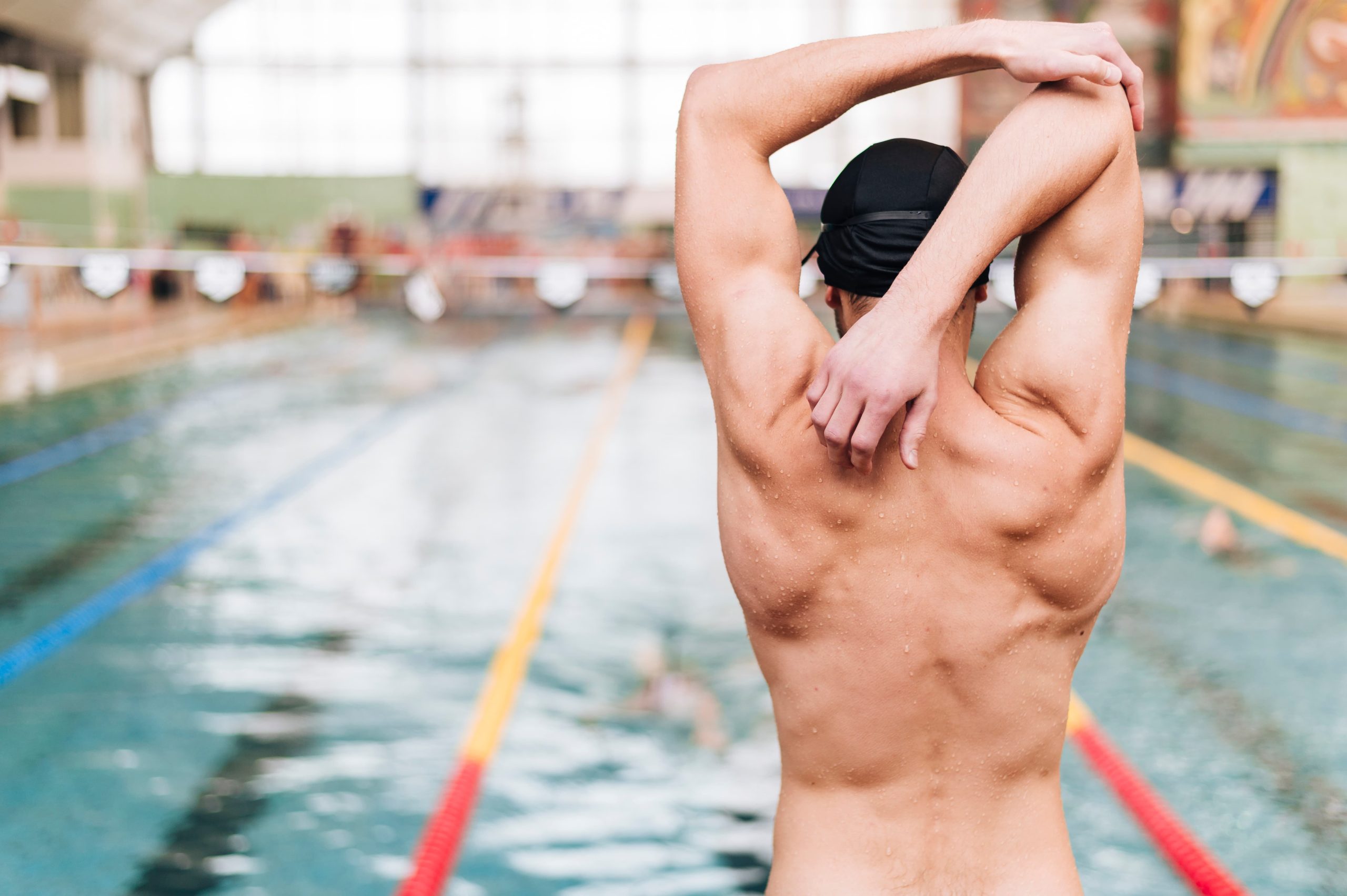 Hombre en piscina listo para empezar su entreno de natación haciendo estiramientos