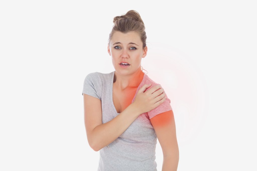 Mujer tocándose el hombro con cara de dolor.