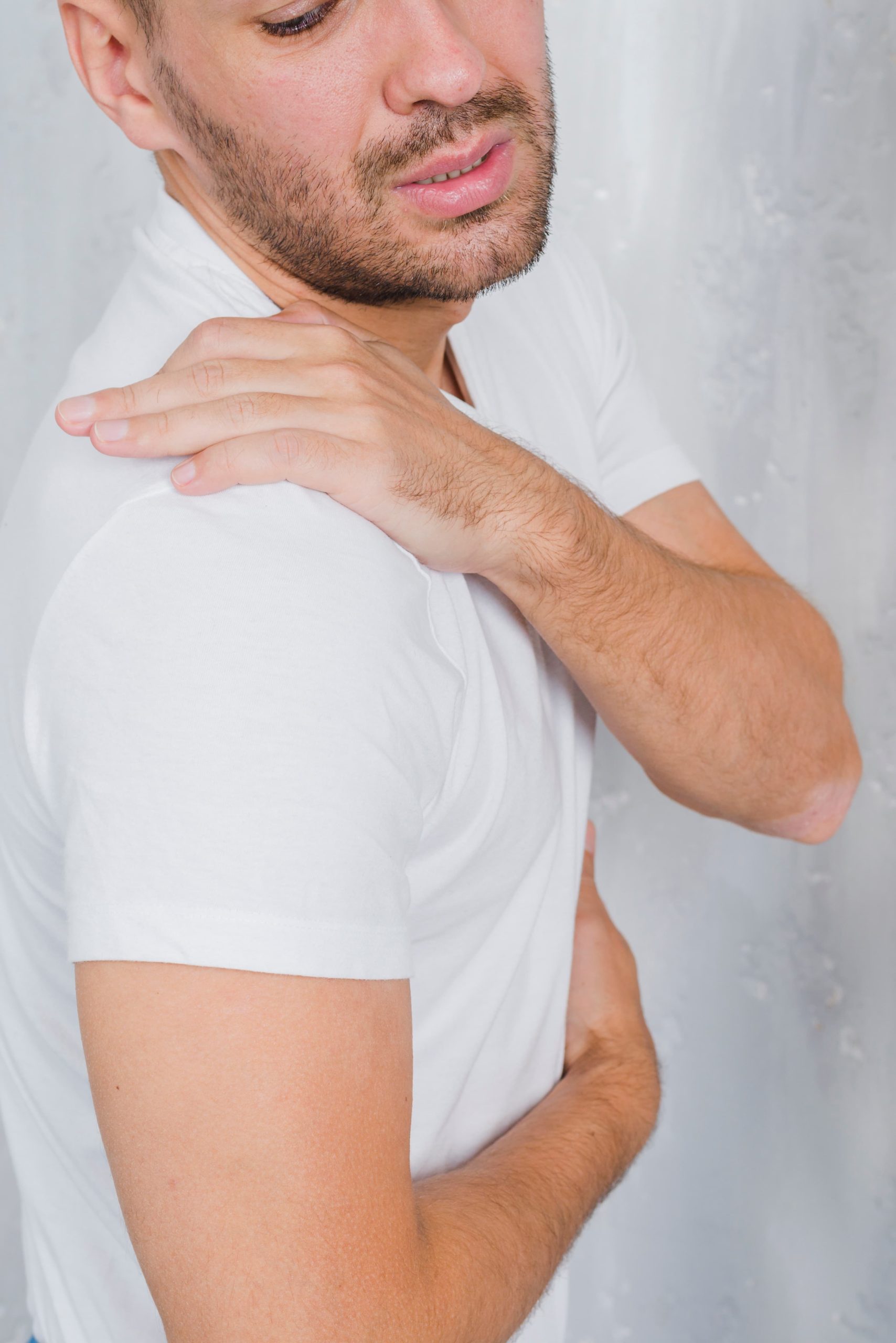 Hombre tocandose eñ hombro con gesto de dolor.