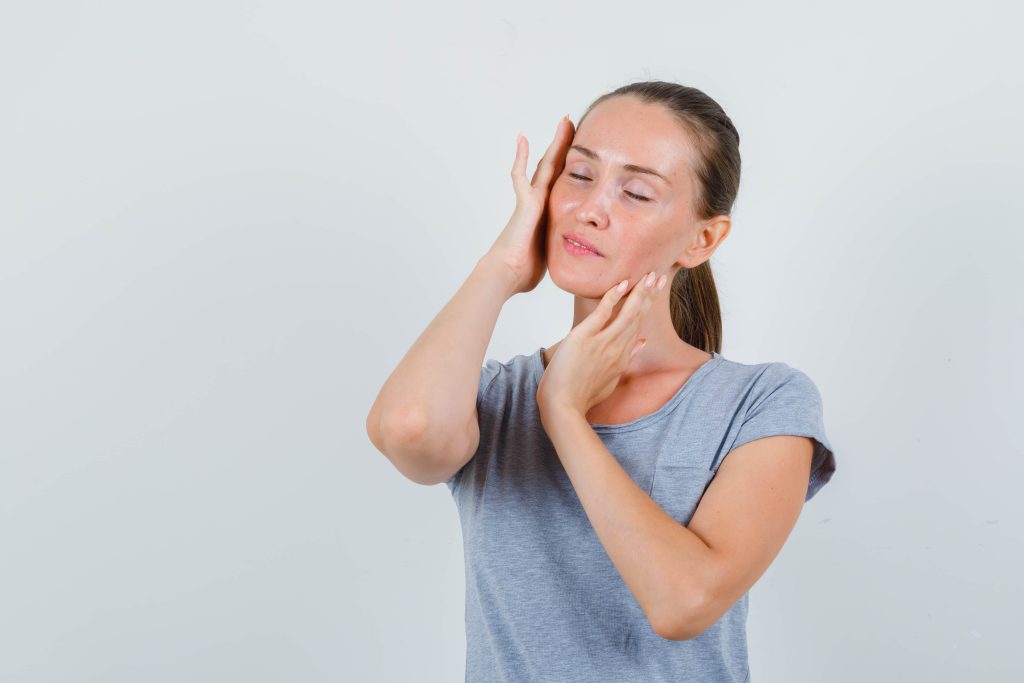Mujer haciéndose un masaje para aliviar la tensión mandibular.