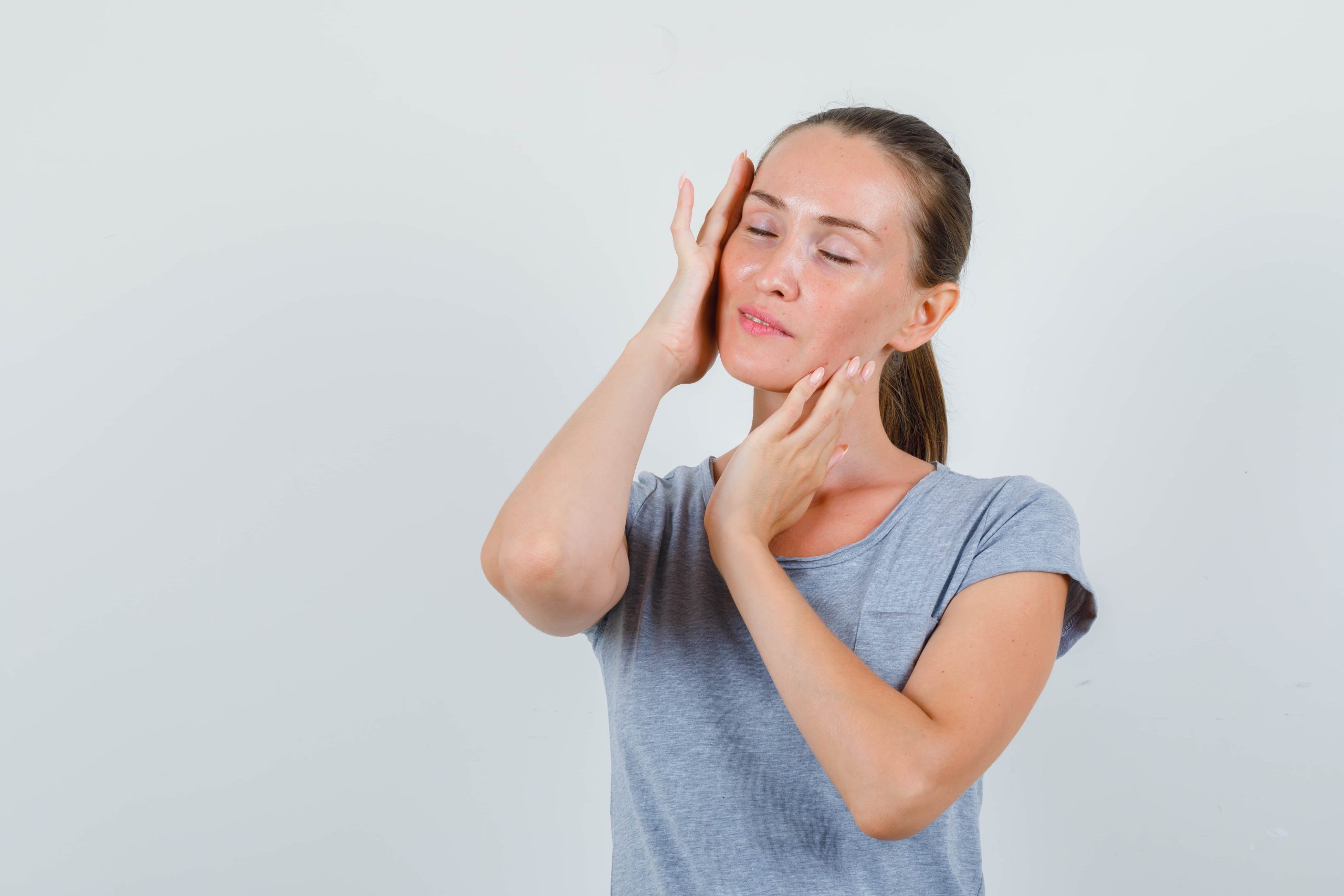 Mujer haciéndose un masaje para aliviar la tensión mandibular.